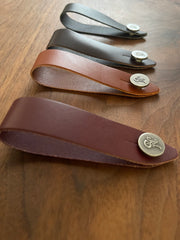 Set of Native Sons Goods leather guitar headstock adapter straps in different colors on wooden surface
