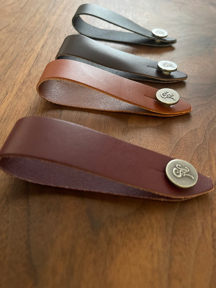 Set of Native Sons Goods leather guitar headstock adapter straps in different colors on wooden surface