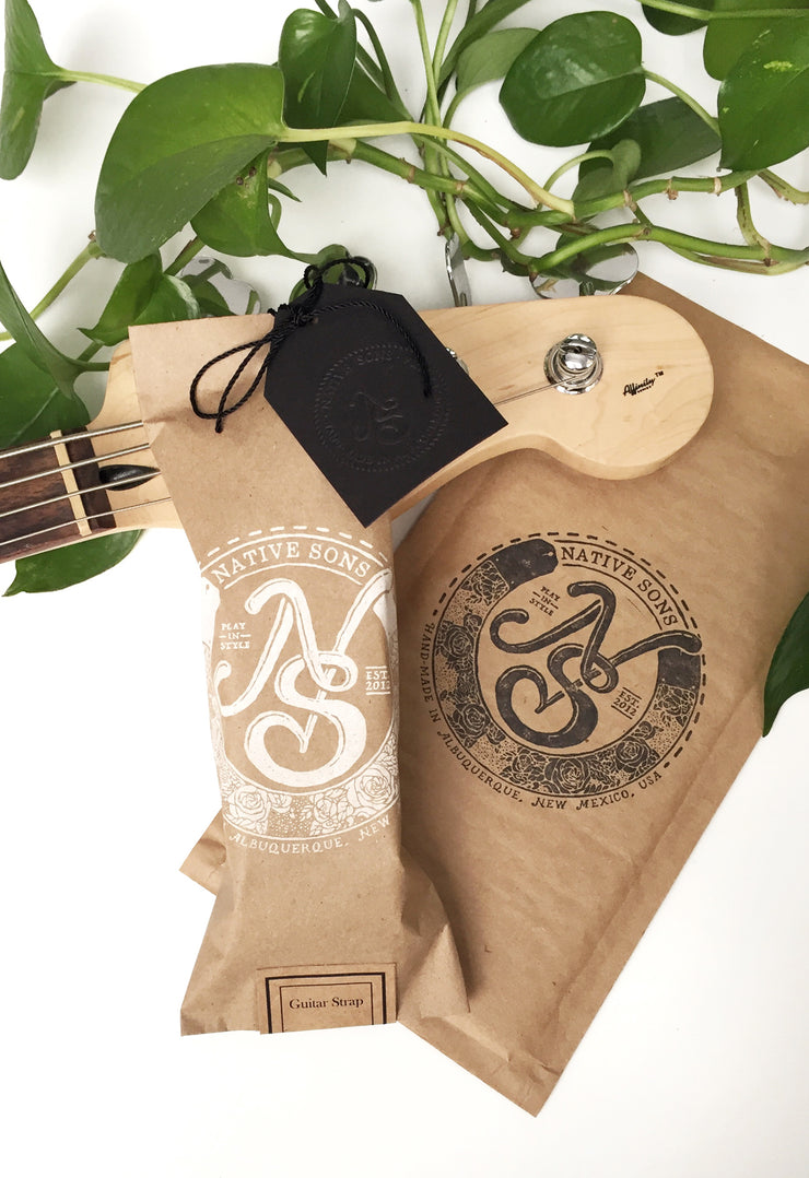 Native Sons Goods vintage style guitar strap in brown packaging with logo and greenery background